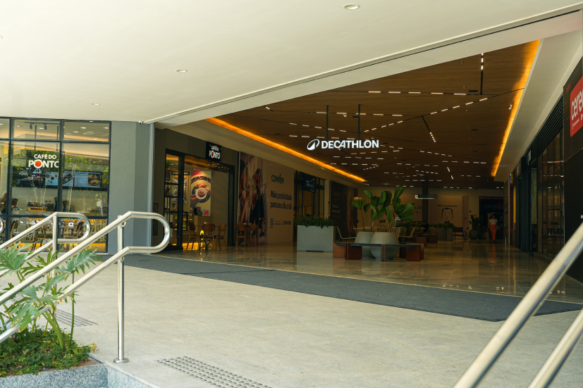 Corredor de centro comercial com lojas de categorias diferentes lado a lado, ilustrando o mix de lojas