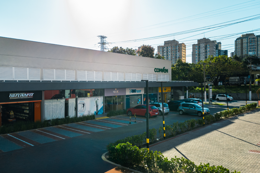 Fachada de centro de conveniência com lojas complementares em bairro urbano.
